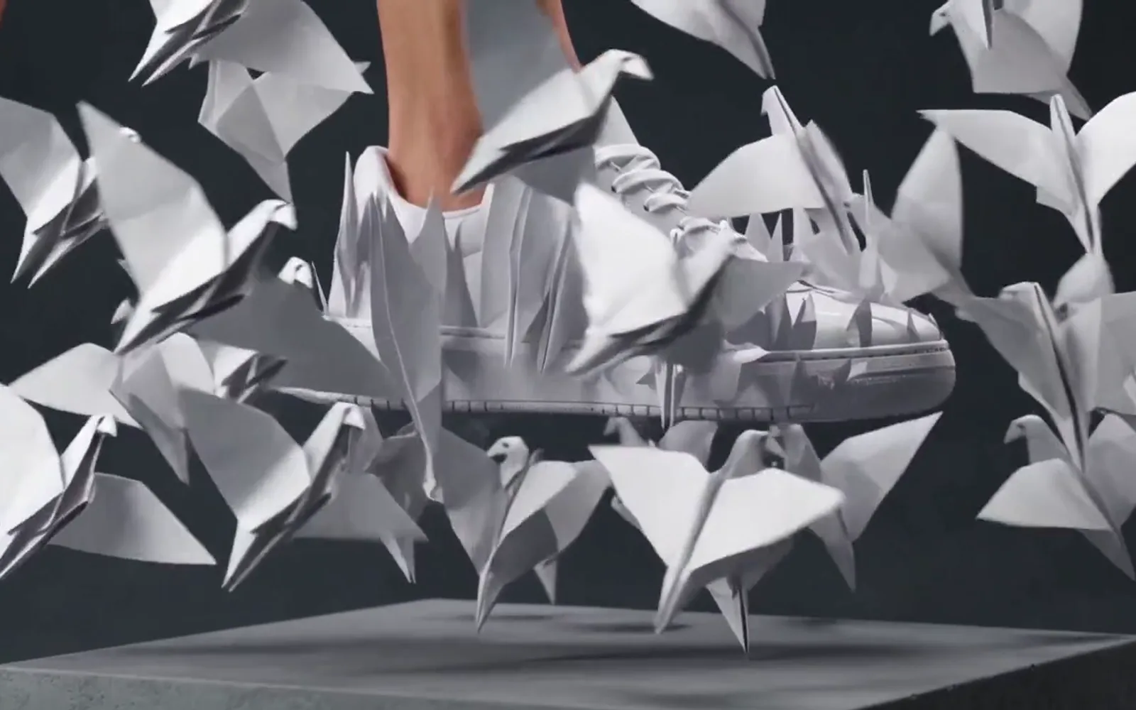 A white sneaker bursting into a flock of white origami birds on a grey plinth, a frame from a Wan 3.0 clip